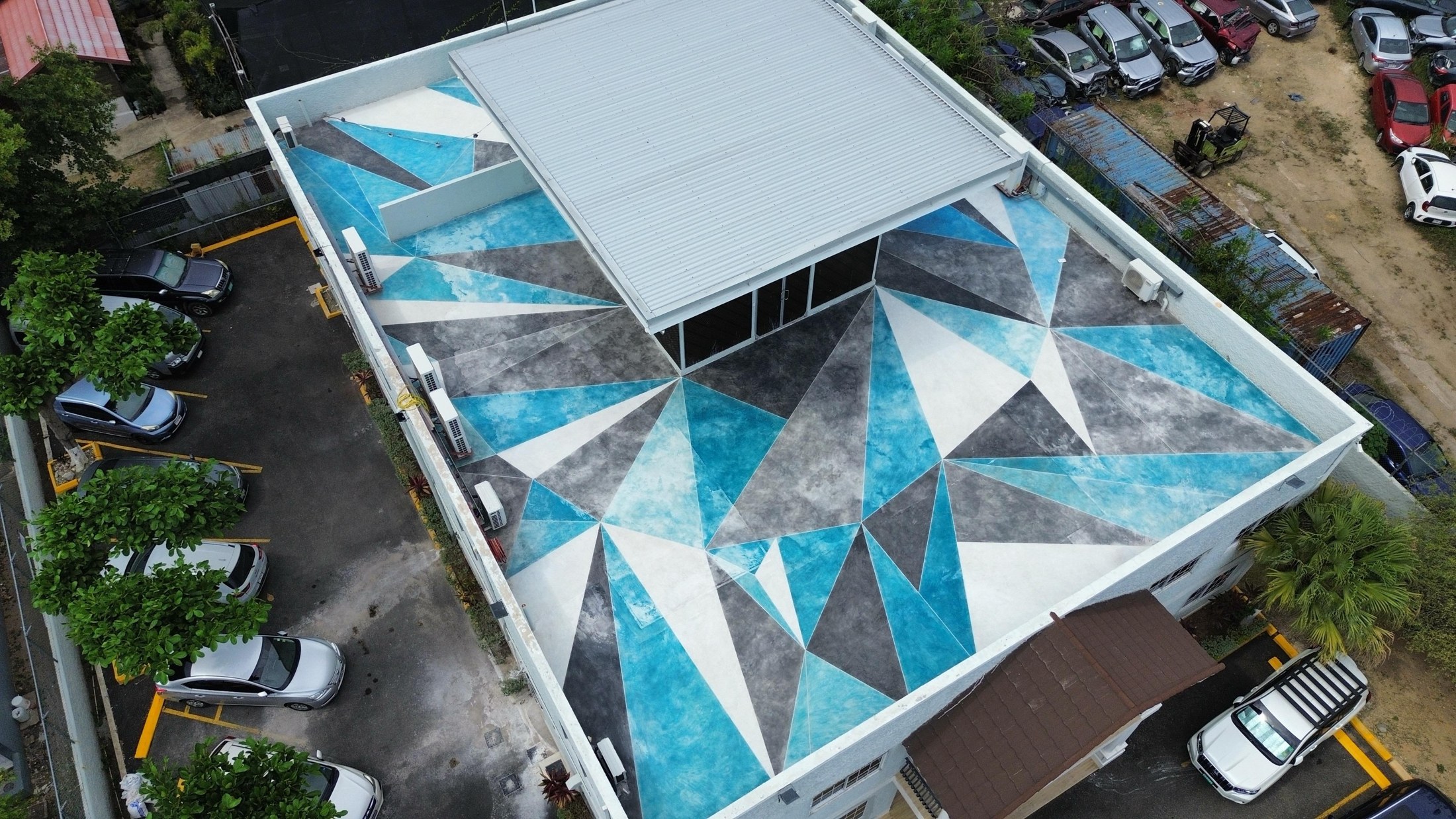Completed Broadcasting Commission of Jamaica rooftop with blue, grey and white triangular patterns around the glazed lobby