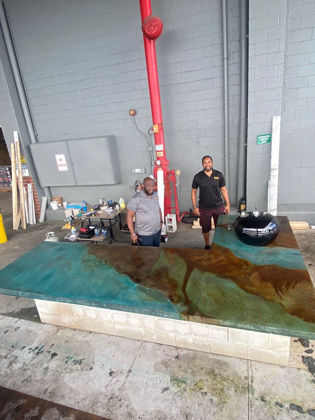 The ExotiCrete team standing behind the finished blue-green stained countertop at SureCrete training