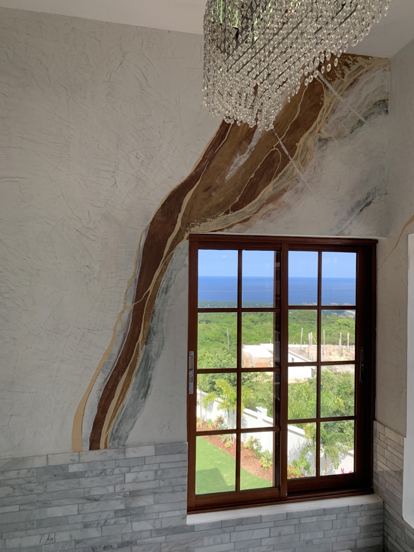 A finished sweep of gold, brown and grey marble-effect plaster frames the sea-facing window.