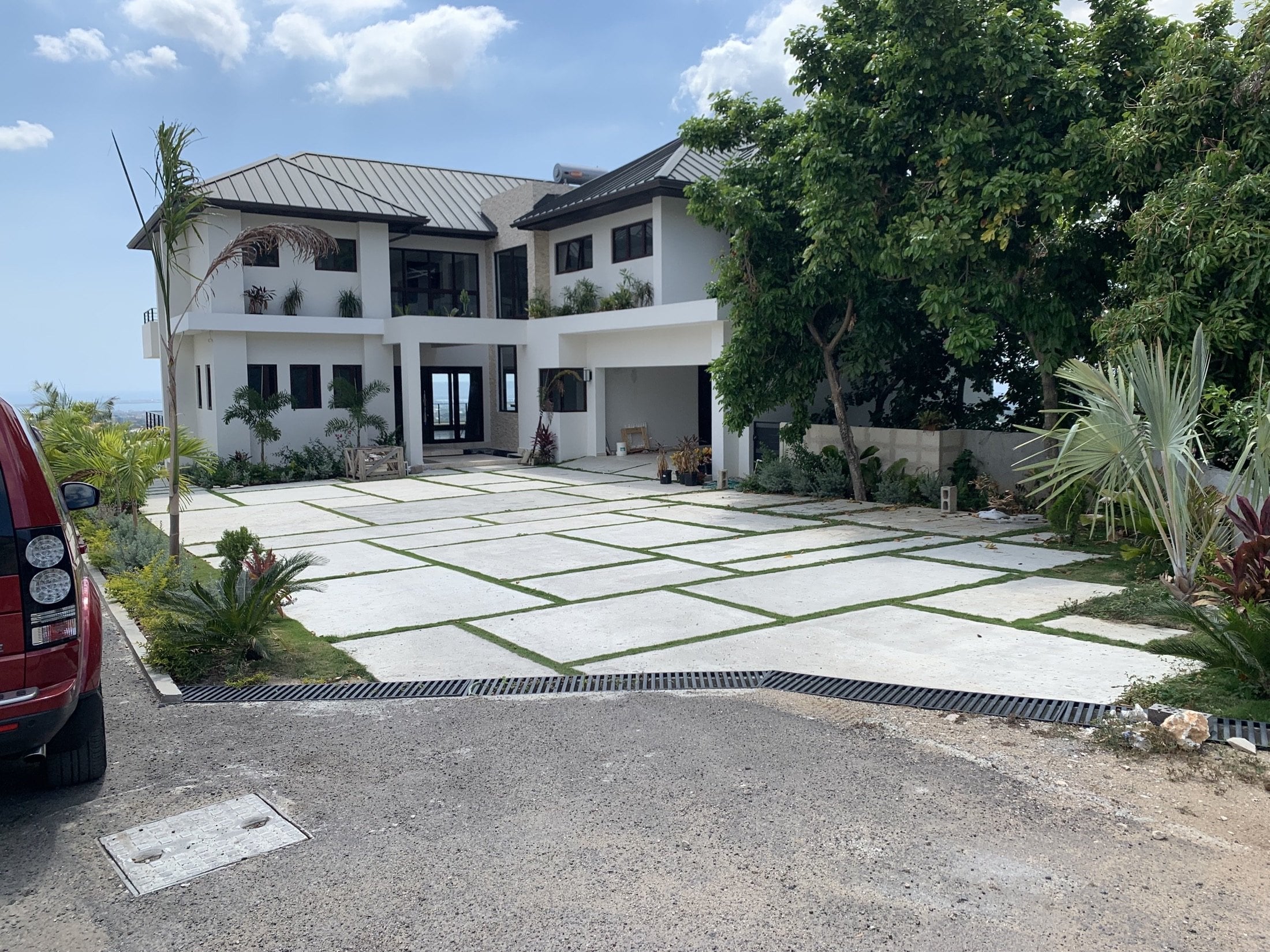 Grass-jointed geometric driveway leading towards the white two-storey house