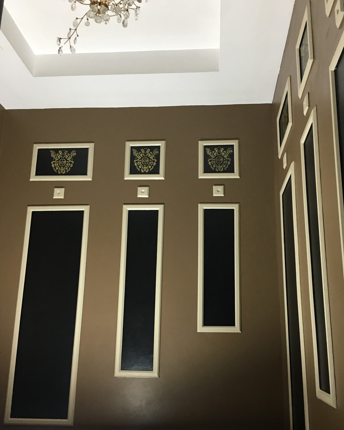Chocolate-brown walls, crisp rectangular panels and hand-applied gold stencil motifs in the Villa Mimosa powder room.