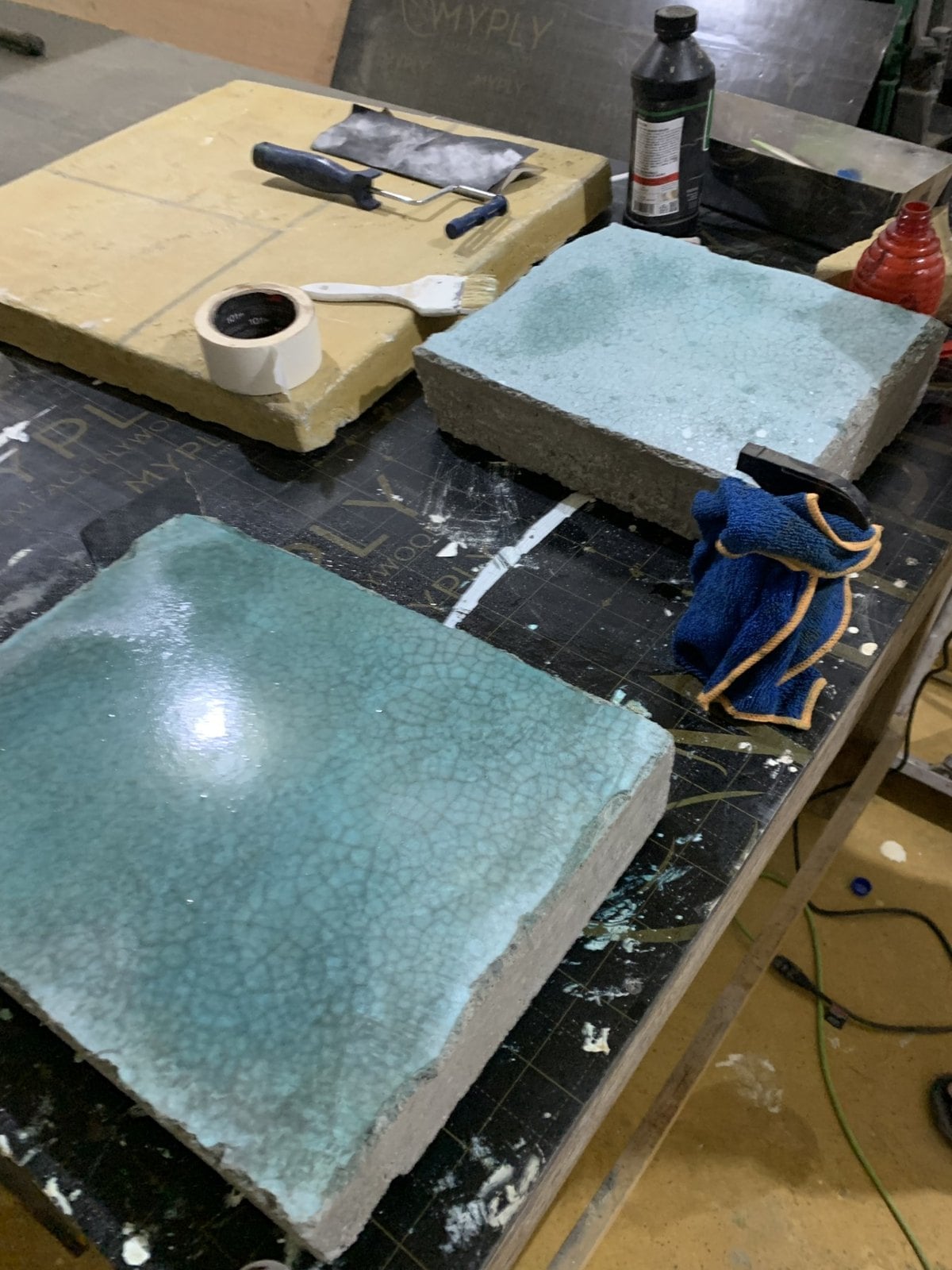 Turquoise, blue and yellow finish sample boards with application tools on a workbench