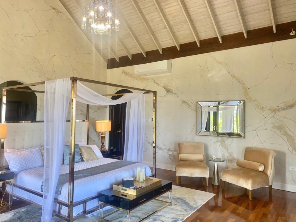 Furnished Villa Mimosa bedroom with hand-applied marble-effect walls, a four-poster bed and vaulted timber ceiling