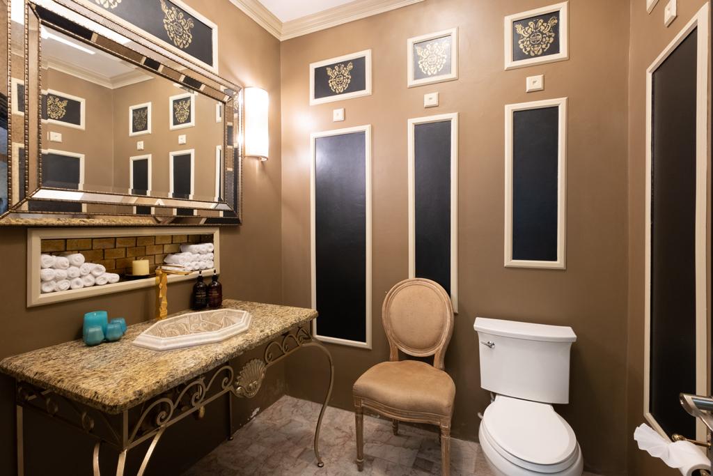 Villa Mimosa’s completed powder room: chocolate-brown walls, cream-edged rectangular panels and custom stencils in the upper squares