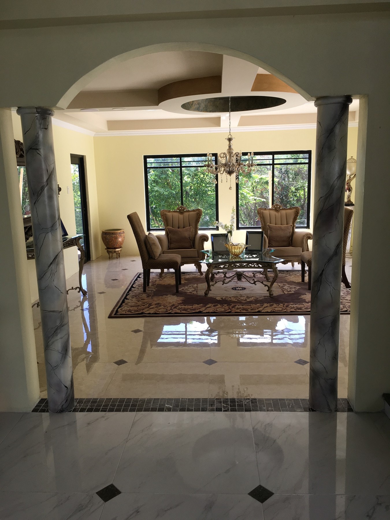 White-and-black Venetian plaster columns framing Villa Mimosa’s furnished sitting room and chandelier.